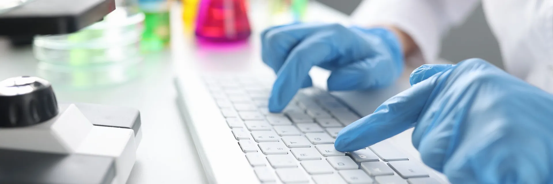 Profissional de laboratório digitando em notebook cercado de equipamentos científicos